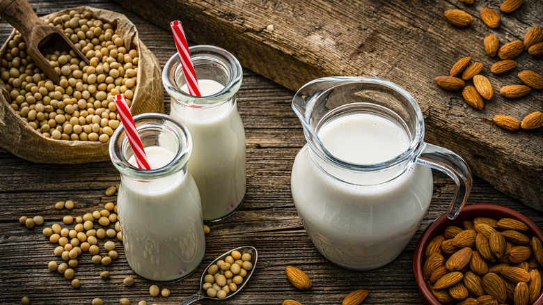 milk jugs with various nuts on wooden surface