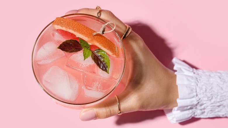 Holding pink drink with ice cubes