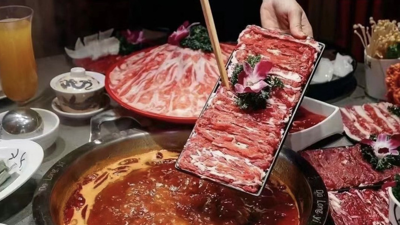 meat going into spicy hotpot