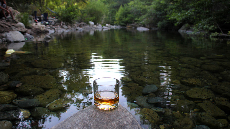 Glass of boubon by river