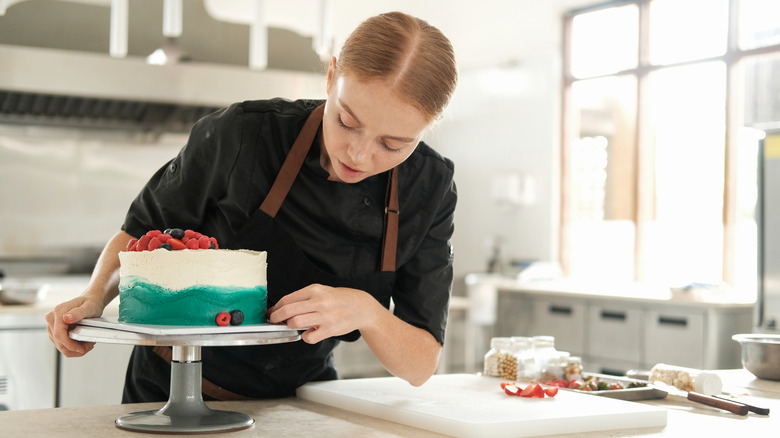 Baker adjusting cake on turntable.