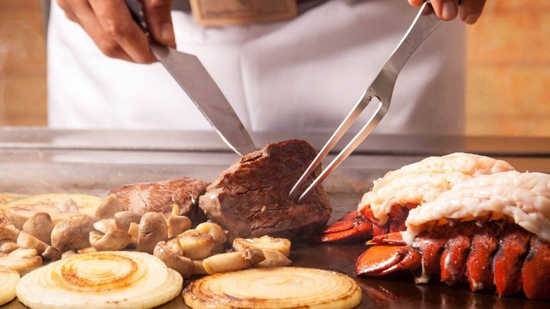 chef lifts steak on grill