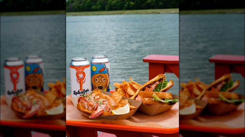 Lobster sandwiches served with beer, with water in the background