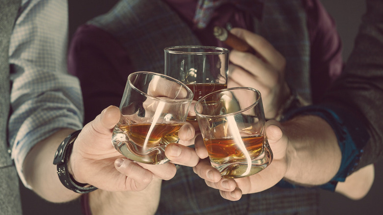 Men clinking glasses of whiskey