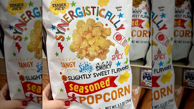 Hand holding white bag of synergistically seasoned popcorn