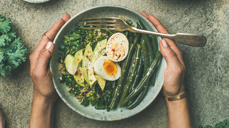 holding bowl with eggs vegetables