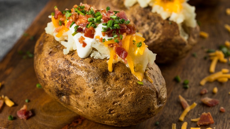 Loaded baked potatoes on cutting board