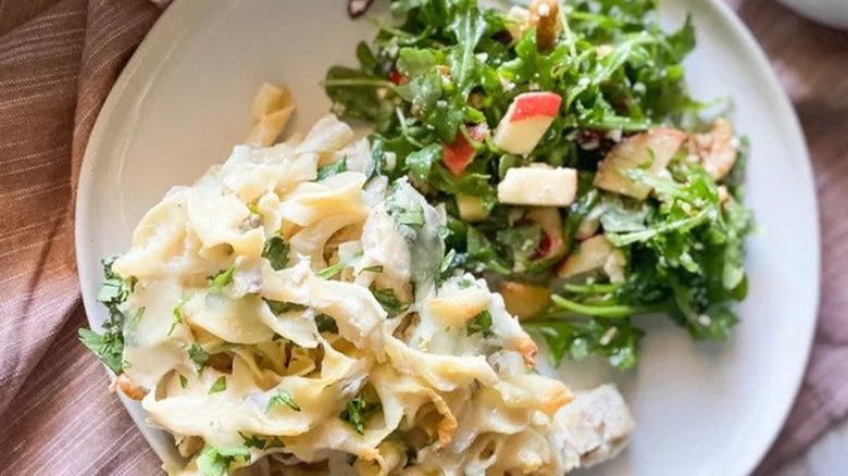 Pasta dish next to salad 