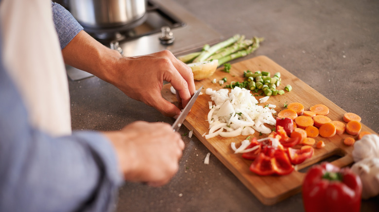 vegetables being chopped on board