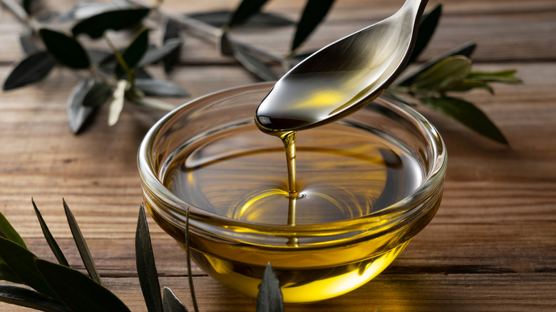 Spooning olive oil into bowl