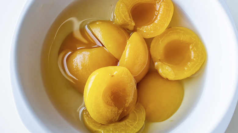 Canned apricot halves in white bowl