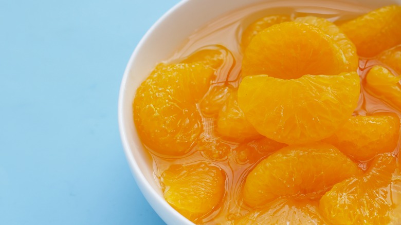 Bowl of canned mandarin oranges on blue background