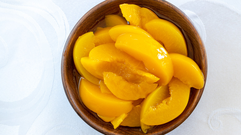 Canned peach slices in wooden bowl