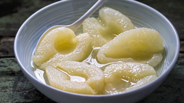 Bowl of tinned pear halves with spoon