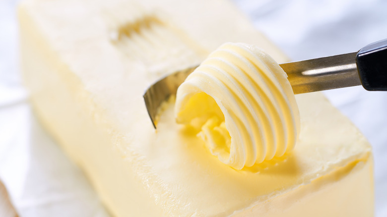 Portion of fresh butter being curled from block