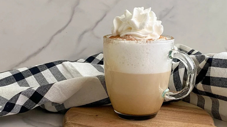 Cappuccino in glass mug with whipped cream