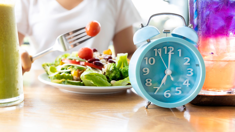 Clock and salad on table