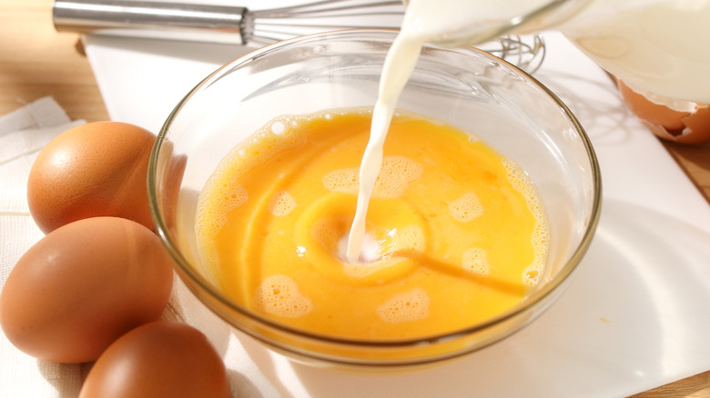 milk cascading into whisked eggs