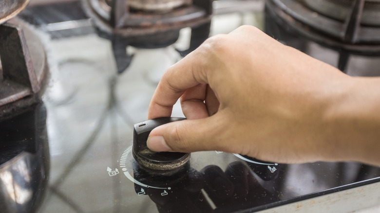 hand turning dial on stovetop