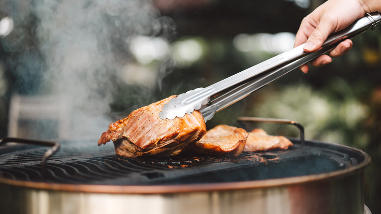 Person using tongs over grill