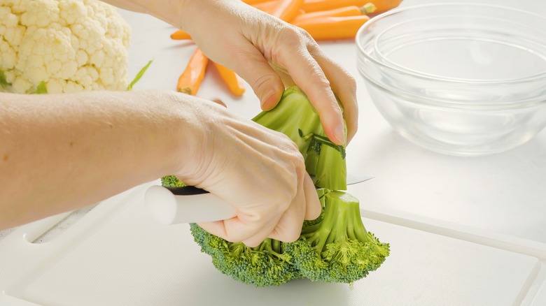 Women cutting off broccoli stem