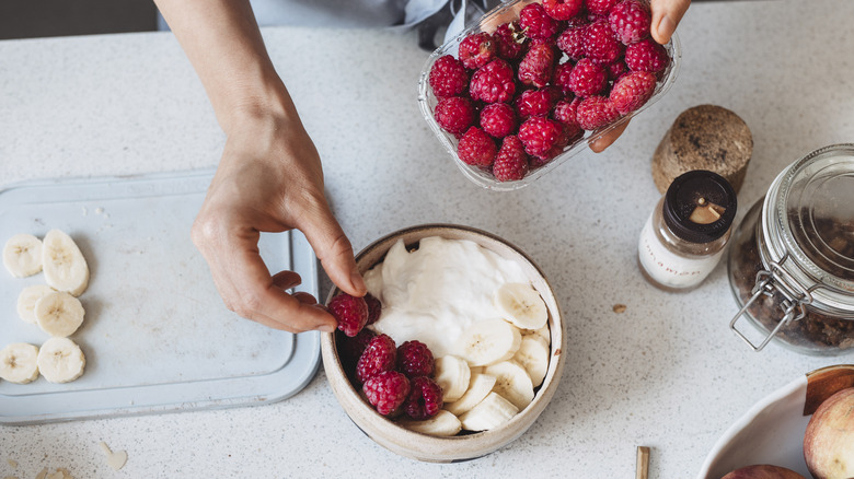 Person placing fruit in yogurt