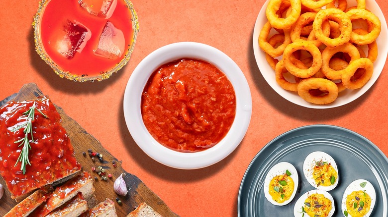 Cocktail sauce in a white bowl surrounded by various dishes against an orange background