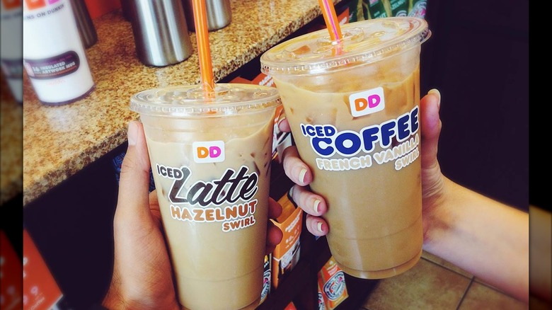 Hands holding Dunkin's Hazelnut Swirl and French Vanilla iced lattes