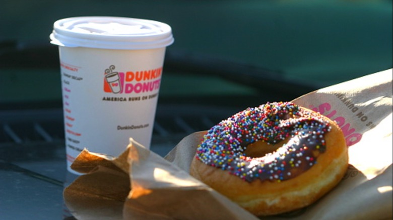 Dunkin' coffee cup and donut with bag outside