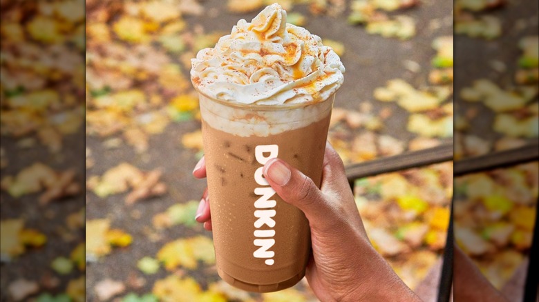 Hand holding a Dunkalatte with autumn leaves