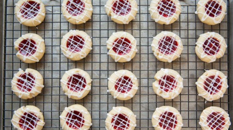 Iced raspberry thumbprint cookies on a baking rack