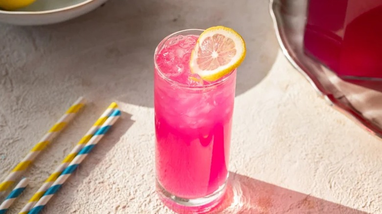 bright pink lemonade in a tall glass with a fresh lemon slice on top