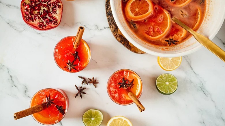 aerial view of multiple glasses of rum punch with a punch bowl next to them