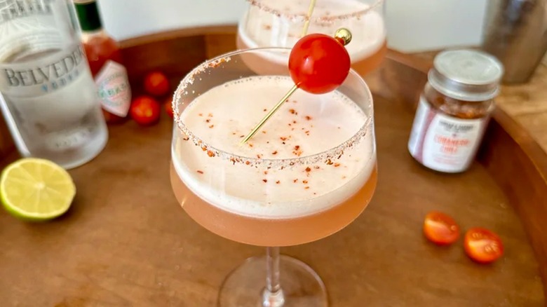 spicy tomato martini on a bar cart with vodka and chile flakes in the background