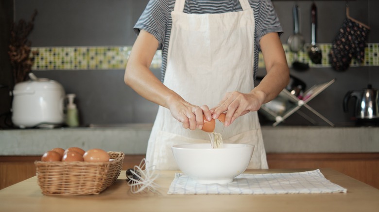 Cook cracking egg into bowl