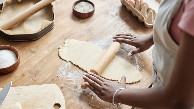 Person rolling out pie crust on wooden surface