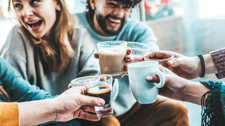 A group of friends enjoying various types of coffee and toasting their mugs