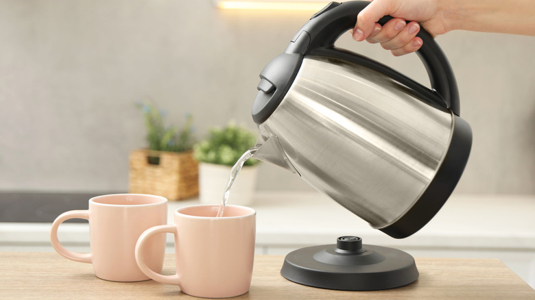 hand pouring an electric kettle into a mug