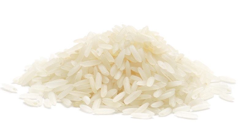Pile of uncooked rice on white 