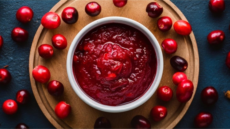 Bowl of cranberry sauce surrounded by whole cranberries