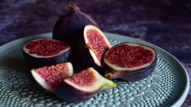 Whole and sliced ripe figs on green plate