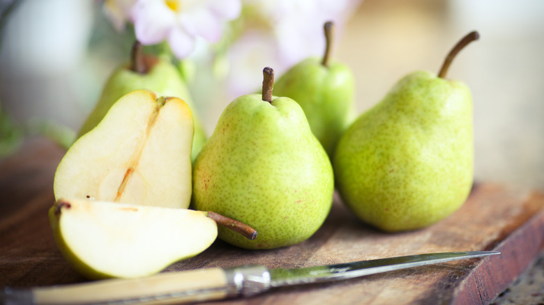 Sliced and whole green pears on a table