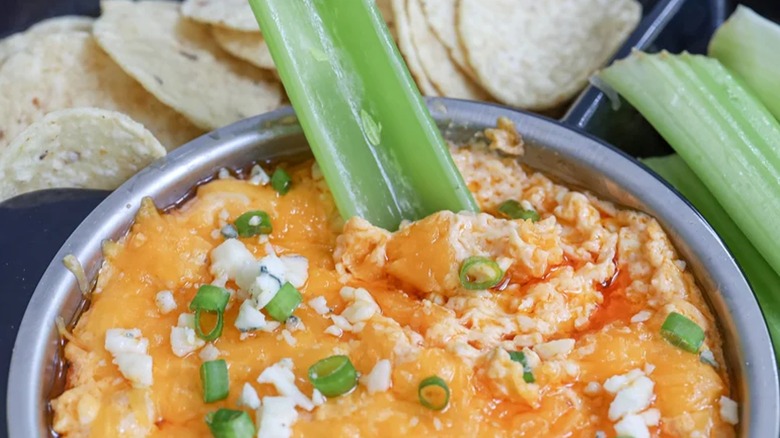 Buffalo chicken dip in a pan with a celery stick