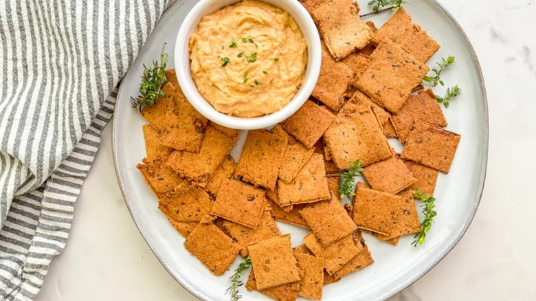 gluten-free garlic and herb crackers displayed on plate with a dip next to it