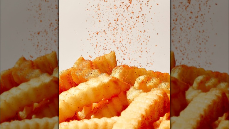 Crinkle-cut fries being sprinkled with Zaxby's seasoning