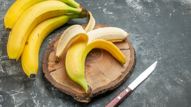 Partially peeled banana on wooden cutting board