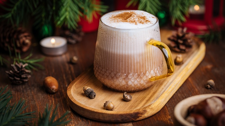 Glass of frothy eggnog latte on wooden serving tray