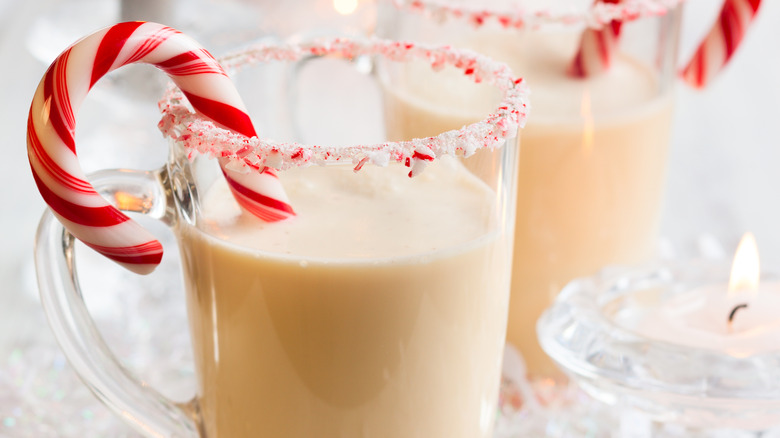 two glasses of peppermint eggnog with candy cane garnishes