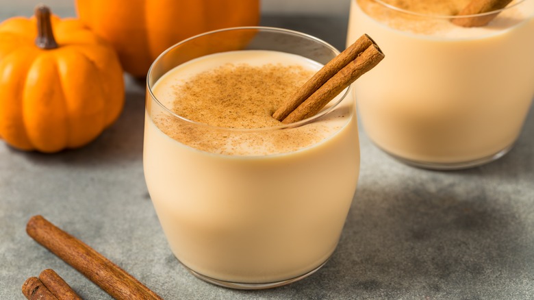 Glass of pumpkin spice eggnog with a cinnamon stick garnish