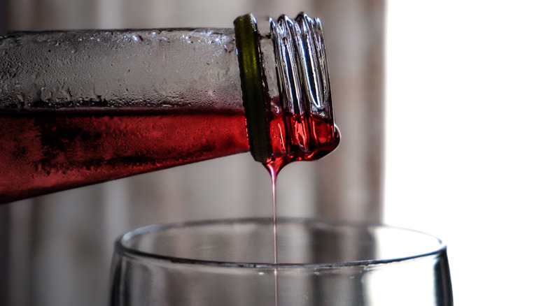 Fruit syrup pouring from bottle into glass